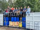 The 3YØK DXpedition team sits atop the packed shipping container that will carry their gear to Bouvet Island for the February 2026 operation. [Kenneth Opskar, LA7GIA, photo]